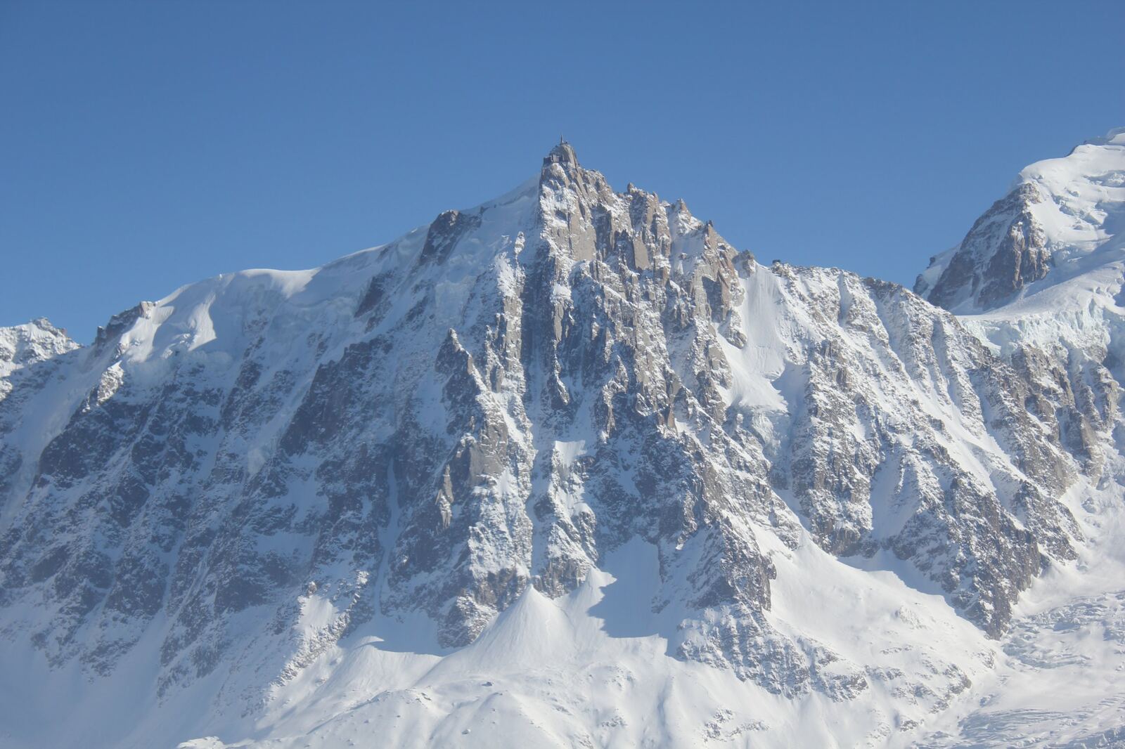 Snow-covered rocky summit under a blue sky